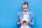 Young trendy caucasian man with blue shirt using a smart phone with blue wall background