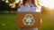 Young unidentified woman holds and hands a box with plastic bottles
