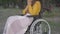 Young unrecognizable paraplegic woman sitting on wheelchair in park and thinking. Caucasian disabled person spending