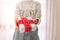 Young unrecognizable woman holds in a gift box in white paper with red twine. Christmas New Years present