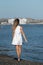 Young unrecognized woman wearing white summer dress walking on beach. Summer holidays