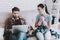 Young Upset Woman Cleaning Room with Lazy Man