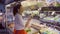 Young vegetarian woman smell and choose green veggies standing in organic shop.