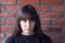 Young very upset brunette woman with bangs wearing a black t-shirt ashamed on brick wall background