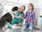 Young veterinary doctor and girl kneeling while looking at dog in clinic