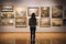 Young visitor admiring various paintings on the wall of an art gallery