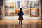 Young visitor admiring various paintings on the wall of an art gallery