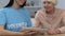 Young volunteer and retired lady scrolling tablet and smiling to camera, banking