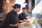 Young wait staff discussing over food with digital tablet and clipboard at counter