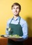 Young waiter greeting customers at table in restaurant