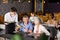 Young waiter serving ordered dishes to senior couple in restaurant