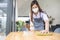 Young waitress with face mask disinfecting restaurant tables