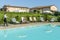 Young waitress serves a poolside cocktail to a customer sitting on a lounger in a resort in the countryside of Pisa, Italy