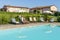 Young waitress serves a poolside cocktail to a customer sitting on a lounger in a resort in the countryside of Pisa, Italy