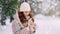 A young warmly dressed woman holds a cup of hot drink in her hands in a winter park.