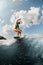 young wet woman in colorful swimsuit energetically balancing on wave on wakesurf board.