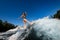 Young wet woman confidently stands on the wakesurf board and rides the wave