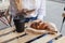 Young white blond woman having a break and holds smartphone in hand. Street veranda table in cafe with cardboard paper