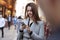 Young white businesswoman standing on a busy London street using smartphone, close up, selective focus