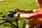 Young white cyclist fixing his helmet while sitting on grass