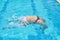 Young white girl with black and white bikini does the somersault in the water of the pool