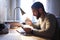 Young white man with a neat beard studying and watching the phone at his desk while taking an infusion