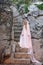 Young white pixie queen in a crown with a veil and a long dress down the stone stairs in a fabulous location