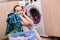 The young wife woman washing clothes near machine