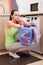 The young wife woman washing clothes near machine