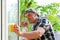 Young window cleaner with a spray detergent onto glass.