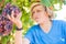 Young winemaker in straw hat examining grapes