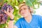 Young winemaker in straw hat examining grapes