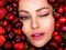 Young, winking girl with bright makeup and a berry background. Happy beautiful caucasian woman