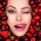 Young, winking girl with bright makeup and a berry background. Happy beautiful caucasian woman sticking her tongue out