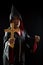 Young wizard show wooden lighting crucifix to exorcise ghost on black background