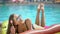 Young woman 20s laying and relaxed near pool at summer holiday. Bikini girl sunbathing lying on inflatable mattresses