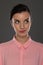 A young woman of 30-35 years old in a pink blouse on a gray background, restrained emotions. Maybe she works in an office