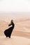 Young woman in Abaya posing in desert landscape.