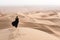 Young woman in Abaya posing in desert landscape.