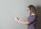 Young woman accusing someone pointing with finger on gray background