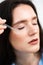 Young woman with acid dropper is applying drops of acid on her skin. Girl applying hyaluronic serum with pipette on face