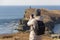 A young woman admires a beautiful view of the sea and rocks at Cape Tobizin on the Russky Island in Vladivostok