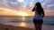 Young woman admiring a gorgeous, vibrant sunrise on the beach