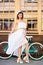 Young woman against vintage bicycle and wall with big windows