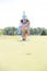 Young woman aiming ball while kneeling at golf course