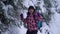 Young woman alone in the snowy woods. Young pretty tourist bounces fun. She`s happy. Snowfall. Slow motion. Close-up.