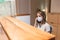 Young woman answer the phone at the reception with coronavirus mask