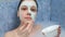Young woman is applying alginate mask lying in bathroom with foam at home.