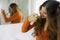 Young woman applying dry shampoo on her hair. Fast and easy way to keep hair clean with dry shampoo. Focus on the hand with spray