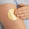 YOUNG WOMAN APPLYING FLESH COLOURED NICOTINE PATCH TO ARM